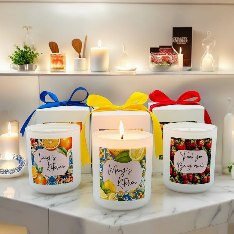 A set of three custom-designed mosaic fruit-themed candles, with options in fresh lemons, juicy oranges, and sweet strawberries, displayed on a kitchen counter.