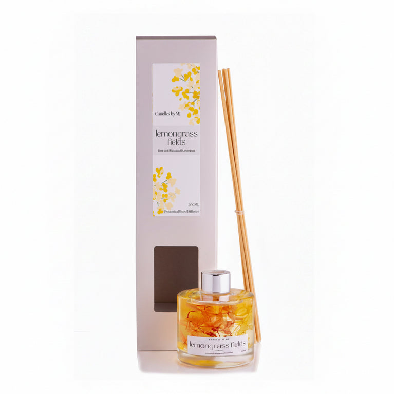 A lemongrass fields reed diffuser with a clear bottle and several reeds placed upright next to it, set against a plain background.