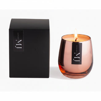 A pink candle with a black label, likely the product 'Lady Million', presented next to its black packaging box with the brand name visible on it.