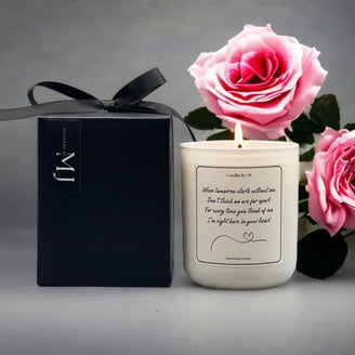 A pink rose next to a black gift box with a sympathy candle inside, both featuring a written message.