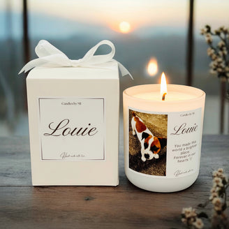 Candle with 'Louie' on it next to its packaging on a wooden surface.